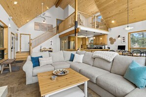 A spacious living area with a large sectional sofa, wooden coffee table, and a staircase leading to an upper level. - 5-Acre Durango Home | Trails, Deck, Mesa Verde (Durango)