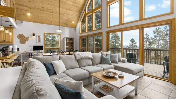 Un espacio habitable amplio con un sofá modular grande, una mesa de centro de madera y un comedor con una cocina al fondo.