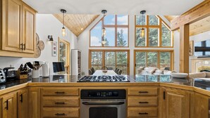 Una cocina moderna con armarios de madera, una isla central y amplios ventanales con vistas al exterior.