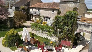 A stone building with a tiled patio, outdoor seating, and a garden. - Hotel the Originals Pigeonnier Du Perron (Availles-en-Chatellerault)