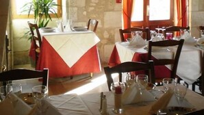 A restaurant with stone walls, red curtains, and tables set for dining. - Hotel the Originals Pigeonnier Du Perron (Availles-en-Chatellerault)