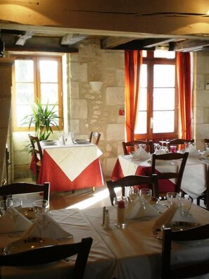 Ein Restaurant mit Stehwänden, roten Vorhängen und gedeckten Tischen.