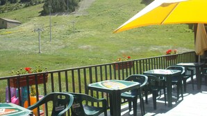 A terrace with outdoor seating, a yellow umbrella, and a view of a green hillside. - Peretol (Bordes d'Envalira)