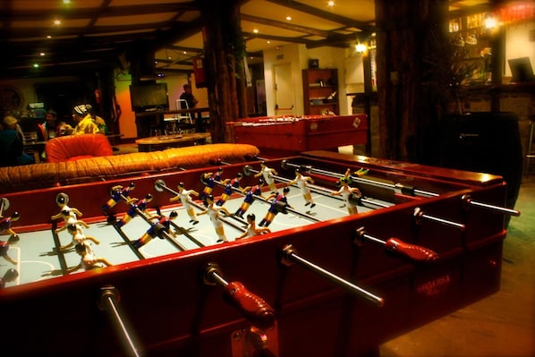 A foosball table in a dimly lit room with wooden beams on the ceiling. - Peretol (Bordes d'Envalira)