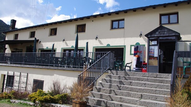 Ein Gebäude mit einer Treppe, die zu einem Balkon führt, einem Red Bull Automaten und dem Eingang eines kleinen Geschäfts.