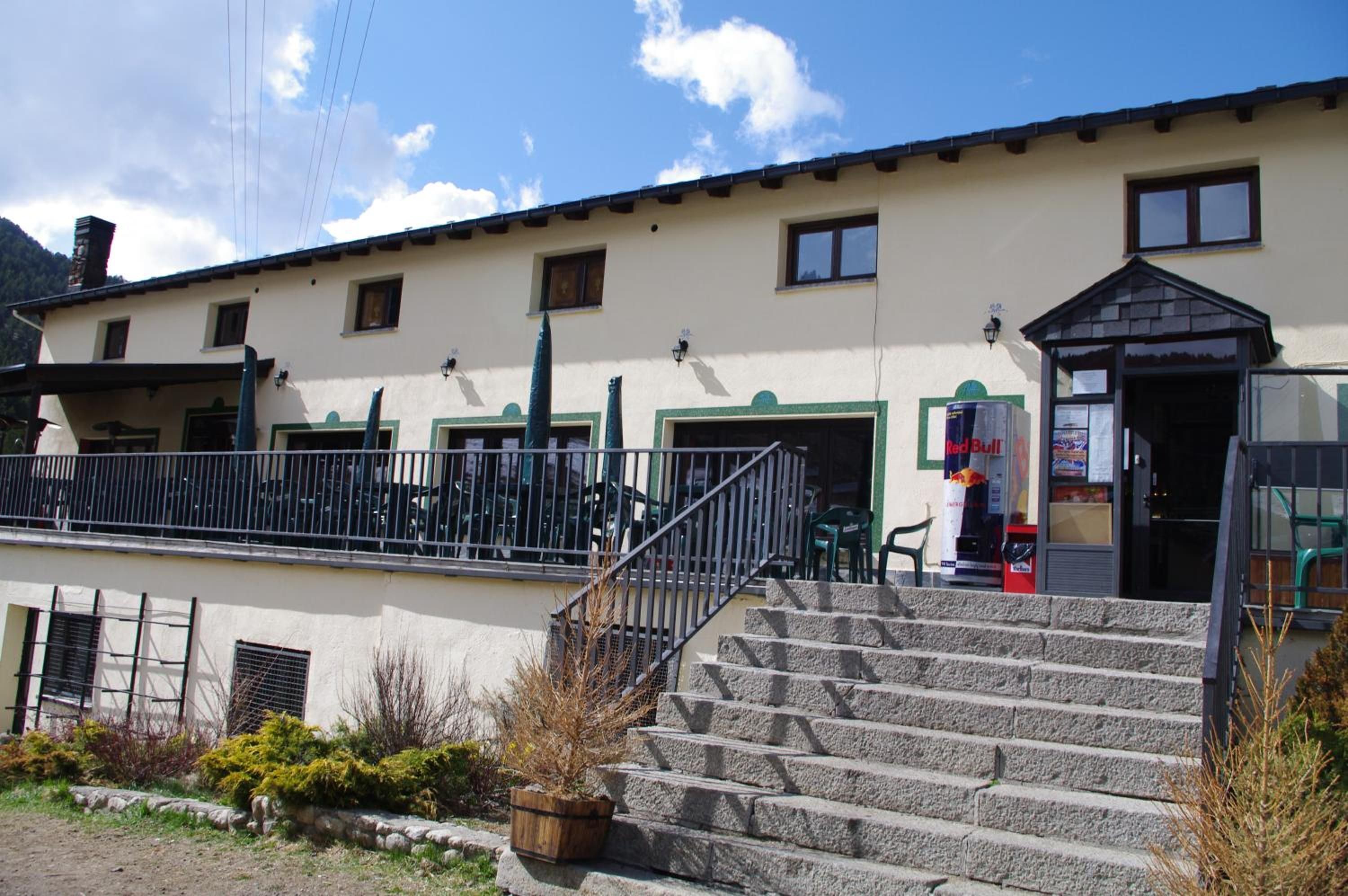 A building with a staircase leading to a door, a Red Bull vending machine, and a small outdoor seating area.