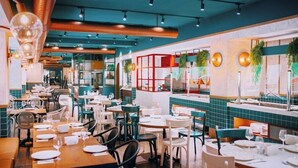 A restaurant with multiple dining tables and chairs, a kitchen area visible through a glass partition, and decorative plants on the walls. - Sairme Hotels & Resorts (Sairme)