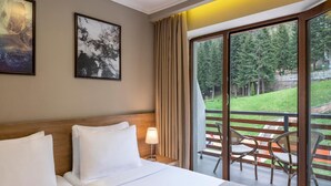 A hotel room with a large bed, a nightstand with a lamp, and a balcony with chairs. - Sairme Hotels & Resorts (Sairme)