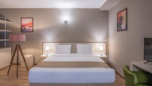 A hotel room with a large bed, bedside lamps, a desk with a chair, a tripod lamp, and two framed pictures on the wall. - Sairme Hotels & Resorts (Sairme)