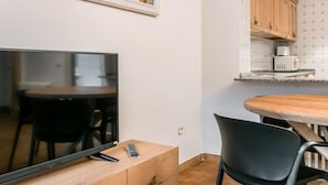 A modern living room with a flat-screen TV, wooden cabinet, and black chairs. - Serrano (Vielha e Mijaran)