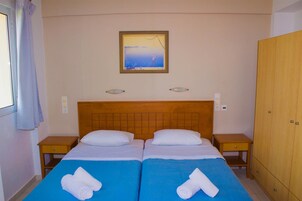 Habitación de hotel con dos camas, cabecero de madera, un cuadro en la pared y un armario.