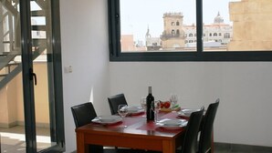 A dining table set with plates, glasses, and a bottle, with a view of buildings through a window. - Apartamentos El Carmen by Be Alicante (Alicante)