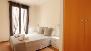 A bedroom with a bed, nightstands, a wardrobe, and a window with curtains. - Apartamentos El Carmen by Be Alicante (Alicante)