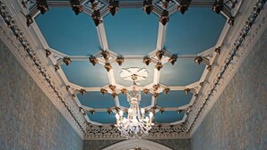 Un pasillo con suelo de madera, puertas blancas y un candelabro.