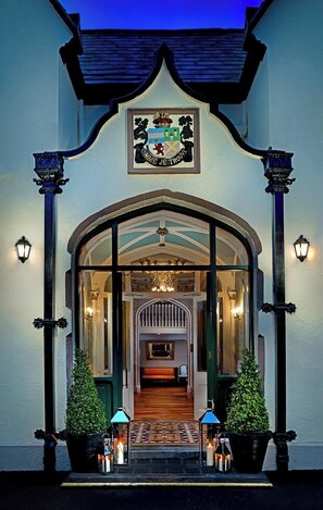 A hotel entrance with a coat of arms, a grand staircase, and a chandelier. - Oranmore Lodge Hotel Galway (Oranmore)