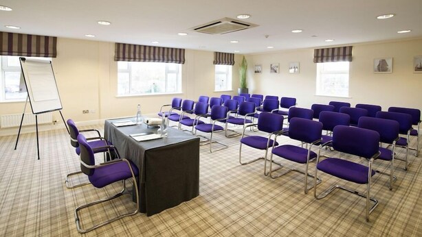 A conference room with a long table, purple chairs, a whiteboard, and large windows. - Carrigaline Court Hotel And Leisure Centre (Carrigaline)