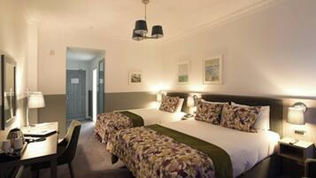 A hotel room with two beds, a desk, a chair, and a door leading to another room.