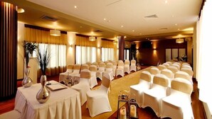 A conference room with rows of white chairs, a long table with a white tablecloth, and decorative vases. - Carrigaline Court Hotel And Leisure Centre (Carrigaline)