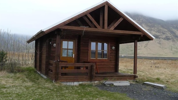 A wooden cabin with a pitched roof, a front porch, and a door. - North Star Guesthouse (Rangárþing eystra)