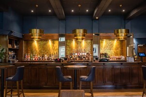 Uma área de bar com balcões de madeira, várias torneiras e assentos com cadeiras.