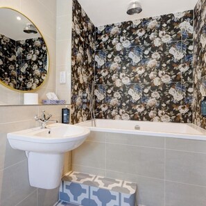 A bathroom with a large sink, a bathtub, and floral-patterned tiles. - Thatchers BW Signature Collection BY Best Western (Leatherhead)
