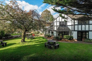 A traditional half-timbered building with a garden and picnic tables. - Thatchers Bw Signature Collection By Best Western (Leatherhead)