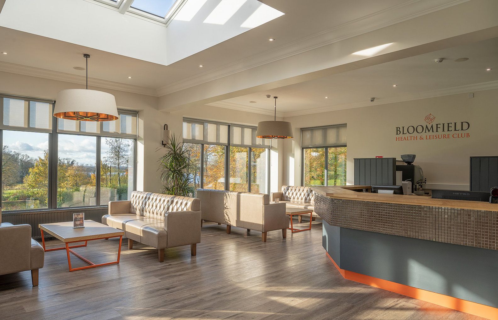 A spacious lounge area with leather sofas, a reception desk, and large windows offering a view of the outdoors.