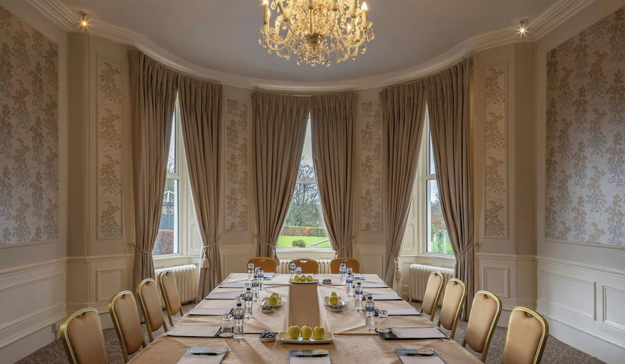 A formal dining room with a long table, chairs, and a chandelier.