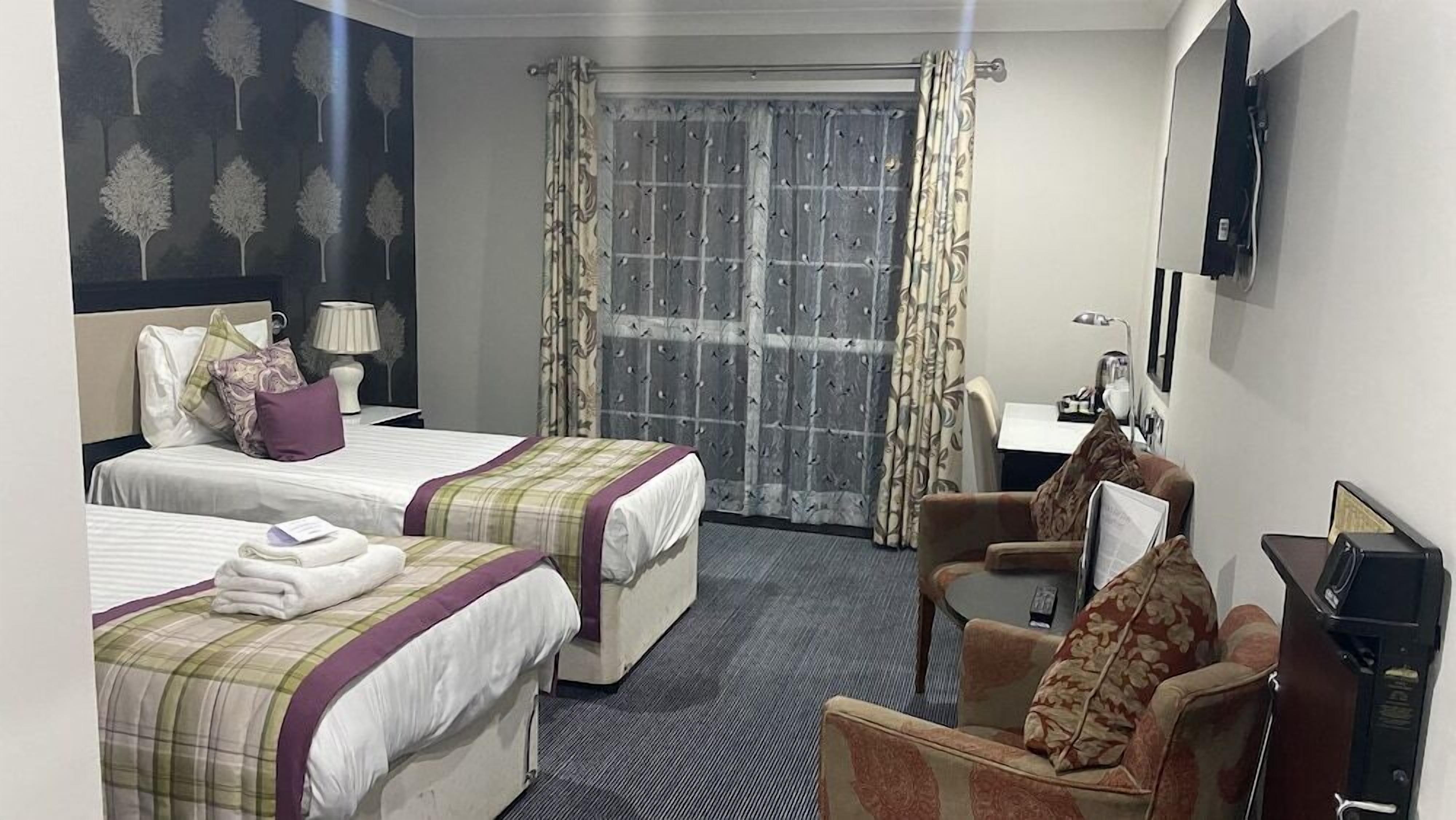 Une chambre d’hôtel avec deux lits, un bureau, une chaise et un téléviseur.