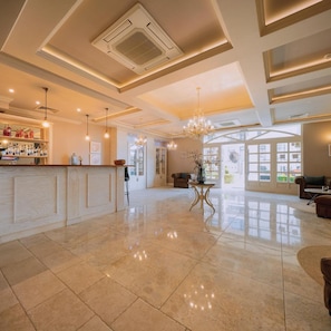 A spacious lobby with a polished tile floor, a bar area with bottles, and a chandelier. - Sunny Castle (Balchik)
