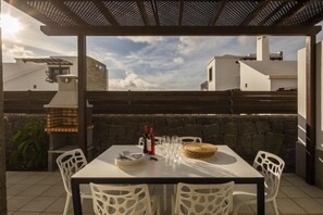 Eine Terrasse im Freien mit Esstisch, Steinmauern und einer Pergola.
