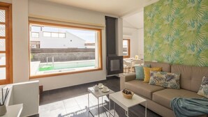 A modern living room with a large window, a fireplace, and a cozy sofa. - Playa Blanca Beach Mate (Yaiza)