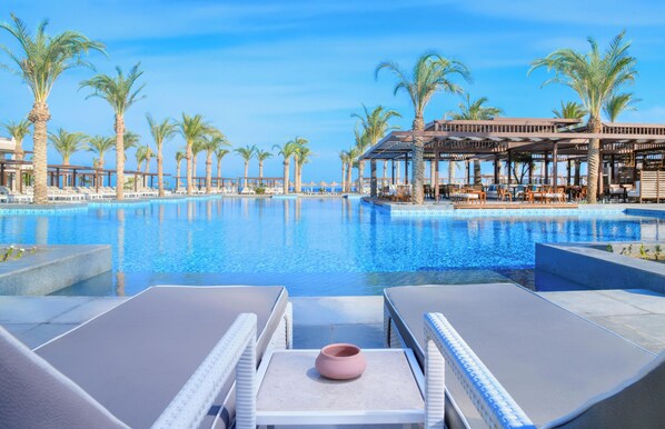 A poolside area with lounge chairs, a table, and a view of the pool and ocean.
