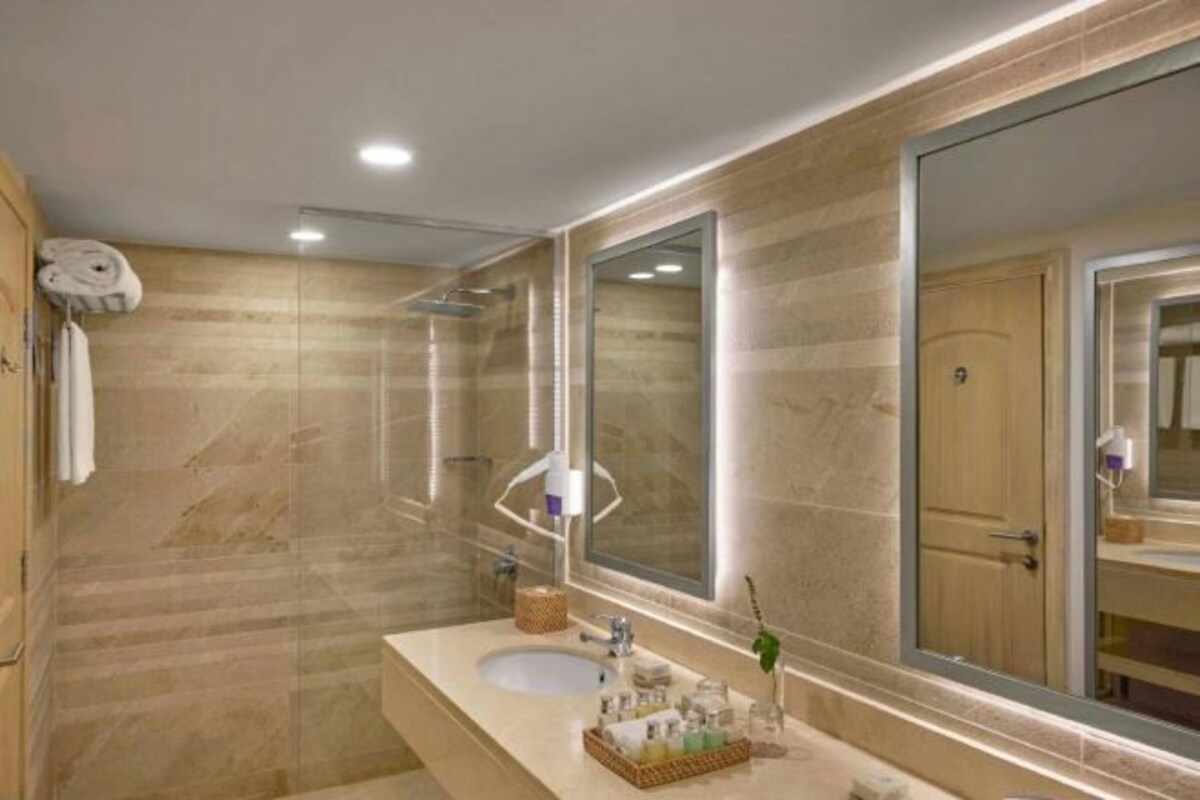 A bathroom with a large mirror, a sink, and a shower.