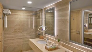 A bathroom with a large mirror, a sink, and a shower.