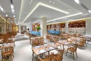 A spacious dining area with multiple tables and chairs, wooden partitions, and a modern ceiling design. - JAZ Costa Mares Adults Only +16 (Marsa Alam)