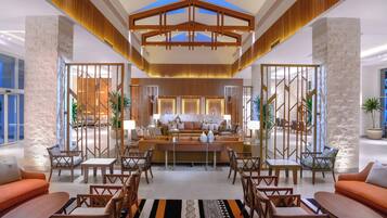 A spacious lobby with a central seating area, a reception desk, and a high ceiling with skylights.