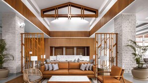 A modern lobby with a sofa, chairs, a coffee table, and a kitchen area in the background.