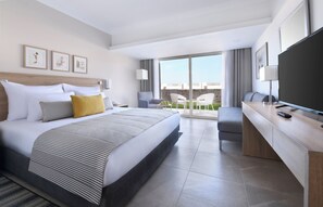 Une chambre d’hôtel moderne dotée d’un grand lit, d’un bureau, d’une tél évision à écran plat et d’un balcon avec vue.