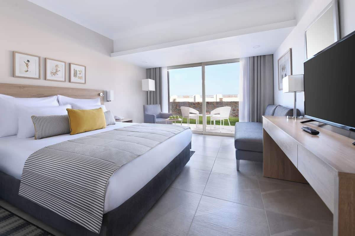 Ein modernes Hotelzimmer mit einem großen Bett, einem Schreibtisch, einem Flachbildfernseher und einem Balkon mit Aussicht.