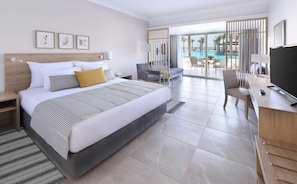 Ein Hotelzimmer mit einem großen Bett, einem Schreibtisch mit Fernseher, einem Sessel und Blick auf einen Pool.