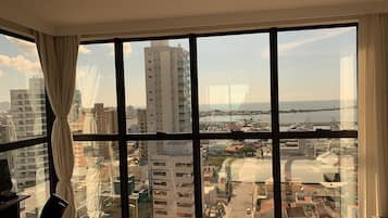 A room with a large window offering a view of a cityscape and a body of water.