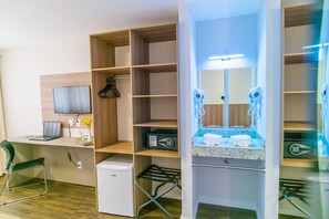 A modern hotel room with a desk, a compact refrigerator, a built-in TV, a large mirror, and a compact kitchenette. - Hotel 7 Itajai (Itajai)