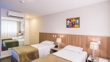 A hotel room with two beds, a wooden headboard, a wall-mounted artwork, and a mirror.