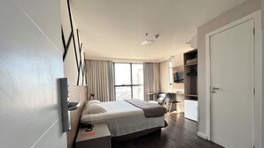 Une chambre d’hôtel moderne équipée d’un lit, d’une table de chevet, d’une télévision et offrant une vue sur la ville.