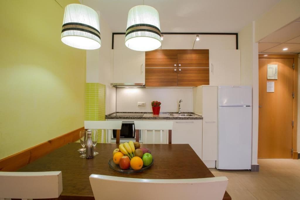 Una cocina moderna con una isla central, armarios blancos y un horno empotrado.