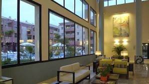 Un'accogliente hall d'albergo con angolo salotto, ampie finestre e vista sugli spazi esterni.