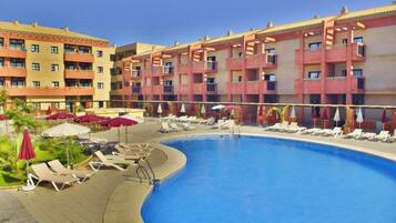 Ett hotell med en swimmingpool, solstolar och parasoller.