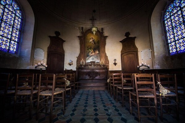 Ein Kircheninneres mit Holzbänken, einem zentralen Altar und farbigen Glasfenstern.
