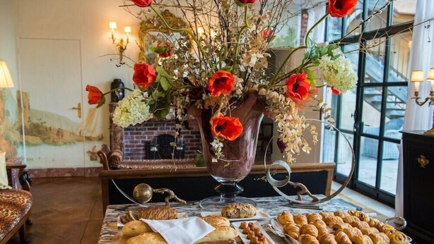A marble table with pastries and a vase of red flowers. - Relais Du Silence Domaine de La Groirie Hotel And Seminars (Trange)